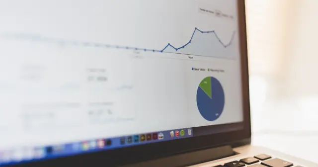 Екран на Google Analytics на лаптоп: линейна графика на посещенията и кръгова диаграма нови срещу завръщащи се посетители